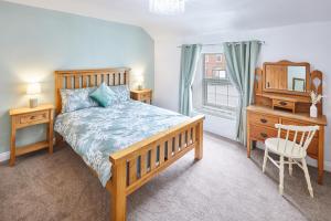 a bedroom with a bed and a chair and a mirror at Poets Cottage in Skinningrove