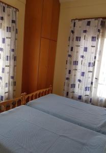 a bedroom with a bed with blue sheets and curtains at Stamatiou Dimitris in Methana