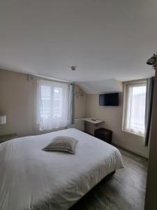 a bedroom with a large white bed with two windows at Hôtel Vauban in Le Palais