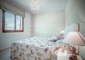 a bedroom with a bed and a lamp and a window at PUSHE Village Playa Granada Beach & Golf 1 in Motril