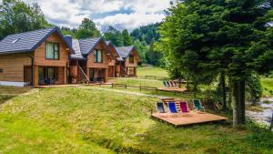 a log home with a bench and chairs on the yard at Novosiele Residence in Bystre