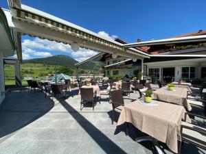 a patio with tables and chairs with mountains in the background at Wohlfühlhotel Berwanger Hof in Obermaiselstein
