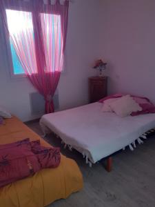 a bedroom with two beds and a window with pink curtains at Le devezou Malons et Elze in Malons-et-Elze