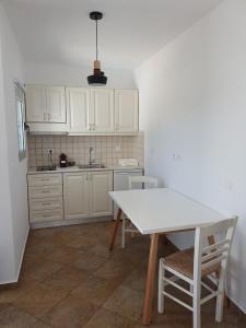 パレカストロにあるGrandes Apartments sea frontの白いキャビネット、テーブルと椅子付きのキッチンが備わります。