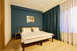 a bedroom with a bed and a blue wall at Apart-hotel TARHUN in Tbilisi City