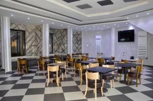 a restaurant with tables and chairs on a checkered floor at Hotel Vallée Des Princes in Douala