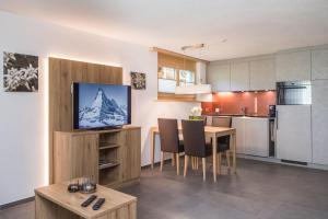 una cucina e un soggiorno con tavolo e TV di Ferienhaus Felicé a Zermatt