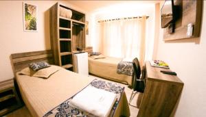 Habitación pequeña con 2 camas y escritorio. en Open Hotel, en Telêmaco Borba