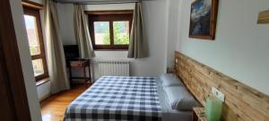 een slaapkamer met een bed met een geruite deken bij Hotelet de Betlan in Betlán
