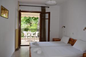 a bedroom with two beds and a balcony with a table at Alexander in Pefkochori