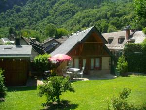 una casa con una mesa y una sombrilla en el patio en petite maison de montagne avec jardin, en Cier-de-Luchon