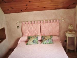 sypialnia z różowym łóżkiem i różowym zagłówkiem w obiekcie petite maison de montagne avec jardin w mieście Cier-de-Luchon