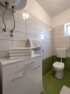 a bathroom with a toilet and a sink with towels at Apartments Laus in Zavalatica +103 photos