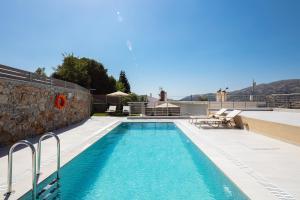 una piscina con acqua blu accanto a un edificio di "Kedros Villa" a luxury touch a Orné