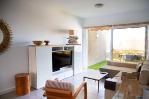 sala de estar con TV, sofá y mesa en Vistas al Mar junto a la playa 3B en Poris de Abona