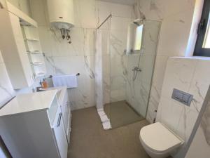 a white bathroom with a shower and a toilet at Apartmani Nešković Foča in Foča +18 photos