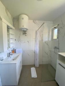 a white bathroom with a shower and a sink at Apartmani Nešković Foča in Foča