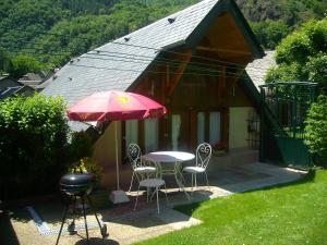 un patio con mesa, sillas y sombrilla en petite maison de montagne avec jardin, en Cier-de-Luchon