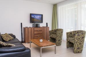sala de estar con sofá, sillas y TV en Ferienhaus Casa Luna, en Zermatt