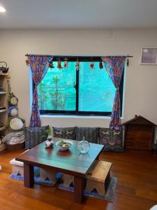 uma sala de estar com uma mesa e uma grande janela em Jiufen Yunhai Yazhu Homestay em Jiufen