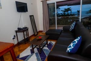 a living room with a black couch and a table at Will's Sea View Apartments in Victoria