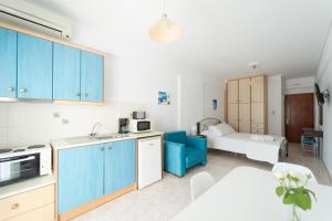 a kitchen with blue cabinets and a room with a bed at Studio Thea in Lixouri