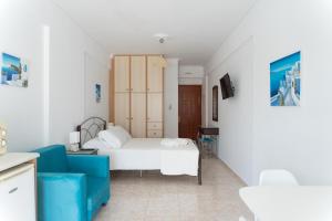 a bedroom with a white bed and a blue chair at Studio Thea in Lixouri