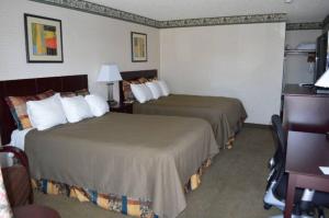 a hotel room with two beds and a desk at Winnemucca Holiday Motel in Winnemucca