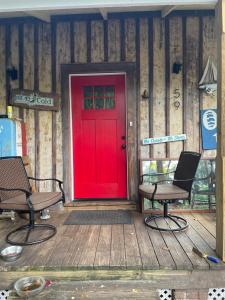 a red door on a wooden deck with two chairs at 150 year old Restored Lincolnville cottage in St. Augustine