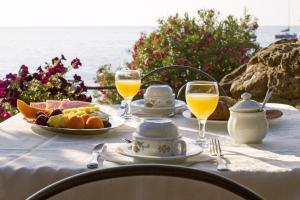 a table with a plate of food and glasses of orange juice at Costa Dorada in Cala Gonone