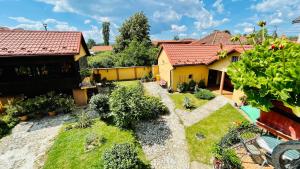 a backyard with a yellow house with a garden at LETO House in Târgu Jiu