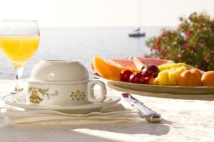 a table with a cup of orange juice and a plate of fruit at Costa Dorada in Cala Gonone