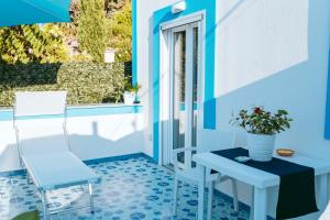 a blue room with a table and a chair and a window at Santa Margherita Suite - CHIAIOLELLA in Procida