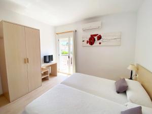 a white bedroom with a white bed and a window at Habitaciones Camping Ferrer in Peniscola