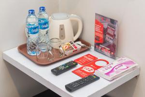 a table with a tray with water bottles and other items at RedDoorz Plus At Merr Rungkut Jl Gunung Anyar in Gununganjar