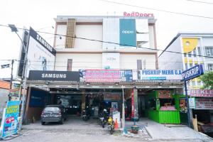 un edificio con cartelli di fronte a un garage di RedDoorz Plus At Merr Rungkut Jl Gunung Anyar a Gununganjar