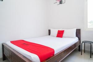 Un dormitorio con una cama con una manta roja. en RedDoorz Plus At Merr Rungkut Jl Gunung Anyar en Gununganjar