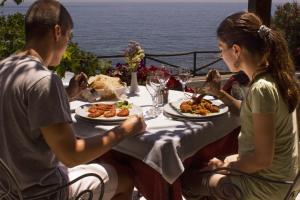 a man and a woman sitting at a table with food at Costa Dorada in Cala Gonone