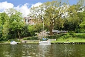 a boat on the water in front of a house at Holly Lodge in Norwich