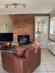 a leather couch in a living room with a fireplace at Holly Lodge in Norwich