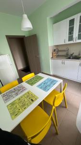 a kitchen with a white table and yellow chairs at IMG Apartment in Sofia
