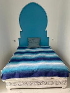 a bed with a blue headboard in a room at Riad Didiss Tetouan in Tetouan