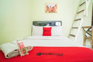 RedDoorz Syariah near Suncity Mall Sidoarjo في سيدوارجو: غرفة نوم بسرير احمر وبيض مع بطانيه حمراء