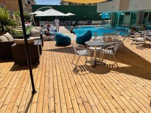 una piscina con tavoli e sedie, un tavolo e sedie di Hotel Apogeo a Rimini