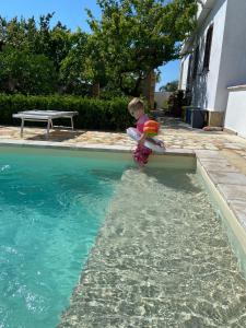 un bambino è seduto accanto alla piscina di Villa Cigaline a Tiggiano