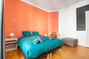 a bedroom with a blue bed with an orange wall at Superbe Appartement Calme 85m², à deux pas du Centre in Nantes