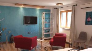 a living room with red chairs and a television on a wall at Apartments Adri, Parking in the yard in Rovinj