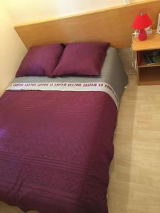 a bedroom with a bed with purple sheets and a table at Mobile home avec parking in Chorges