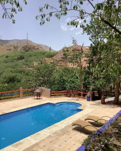 a pool with chairs and a table and a mountain at Jnane Karma in Imlil