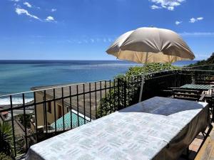 a balcony with a table and an umbrella and the ocean at Ocean View Villa with Fast WI-FI and Elevator to Town in Levanto